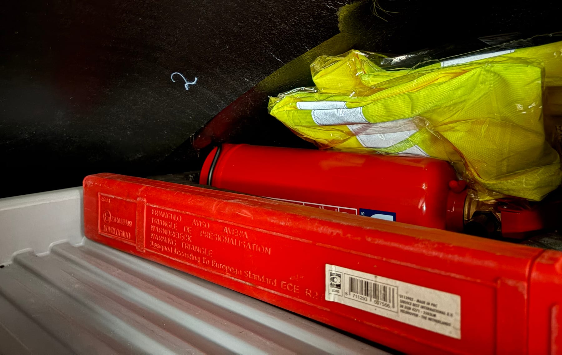 Brandblusser en veiligheidshesjes in het opbergvak boven de bestuurderscabine.