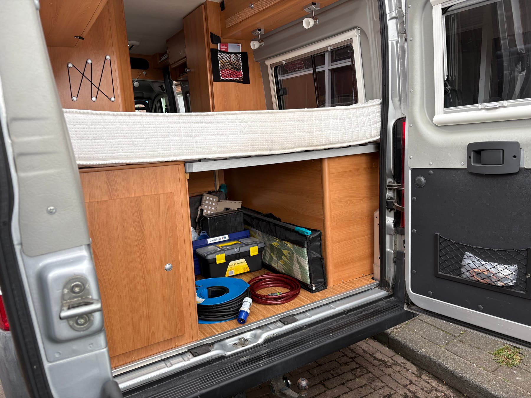 Garage achterin de camper met onder andere de stroomkabel en tuinslang.